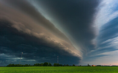 Extreme thunderstorm shelf cloud moving over fields, climate change concept