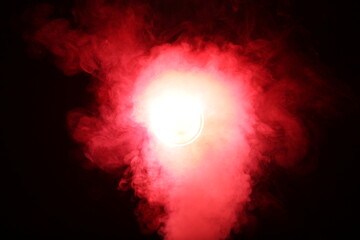 Artificial magic smoke in red light on black background