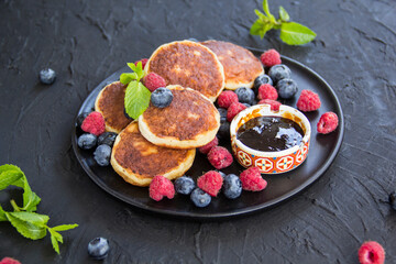 A healthy breakfast of cheese pancakes, berries, and honey. Creative atmospheric decoration