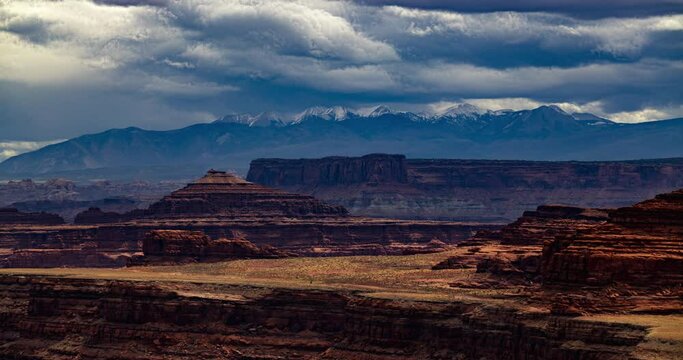 Time lapse of clouds rolling over high mountains in a red desert landscape