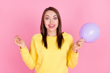 Photo portrait girl smiling keeping purple air balloon preparing to party in yellow sweater isolated pastel pink color background