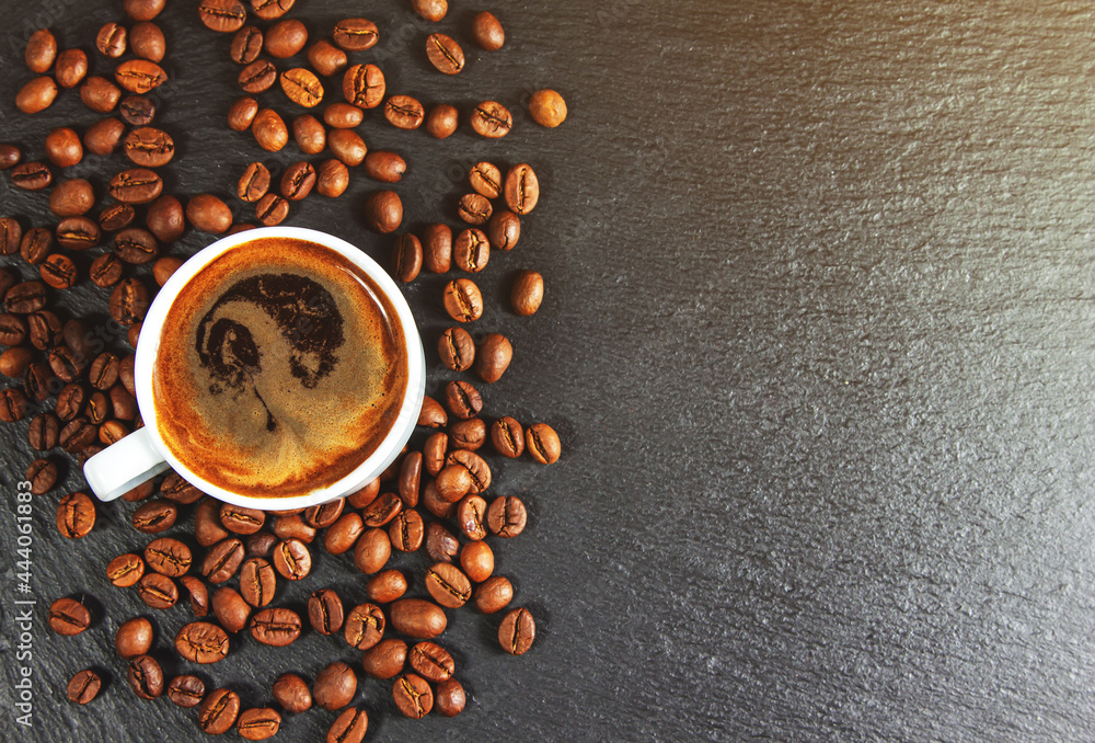 Wall mural a cup of coffee on a black background with roasted coffee beans. top view