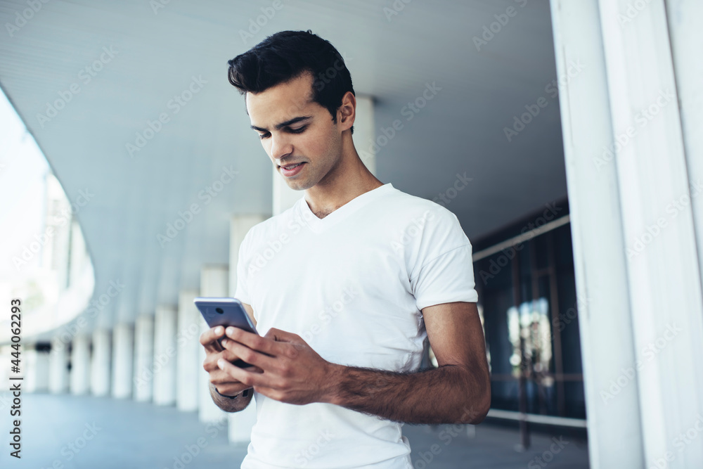 Poster young hipster guy in casual clothes connecting to wireless for chatting and messaging in social medi
