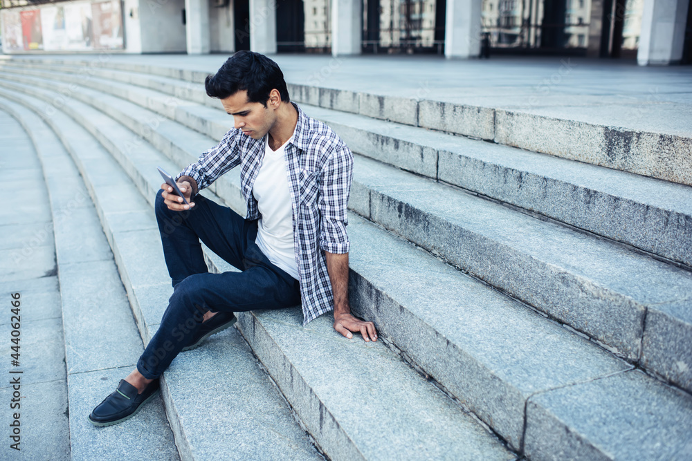 Poster caucasian hipster guy in casual clothes using cellular technology for online messaging in networks, 