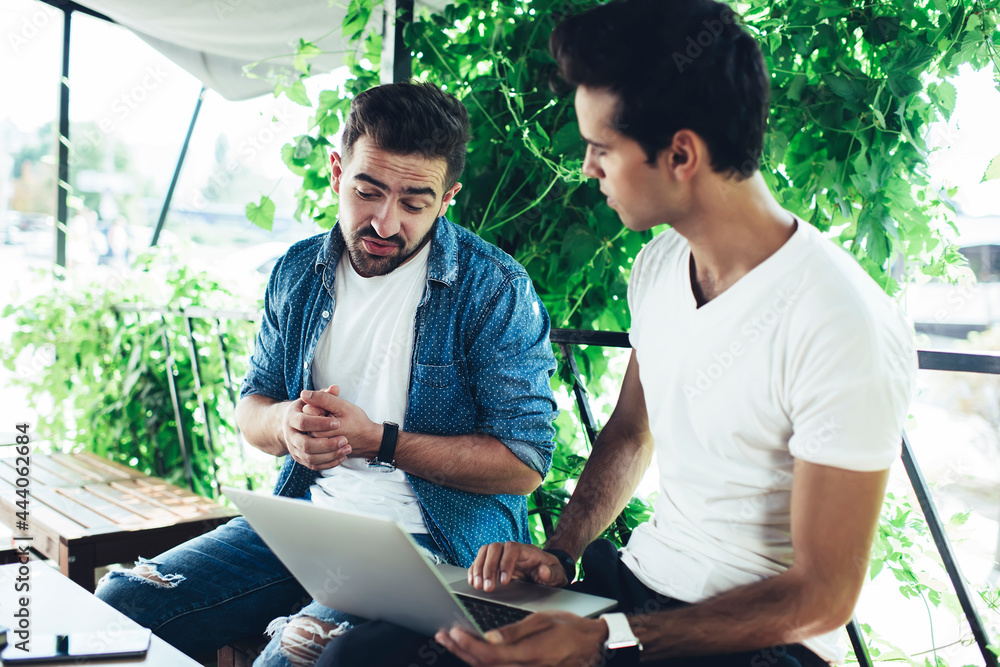 Poster caucasian male programmers discussing software developing during collaborative meeting in street caf