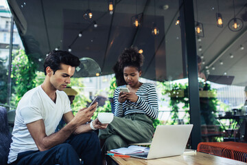 Multiracial male and female colleagues ignoring live communication prefer social networking with virtual followers, millennial hipster guys using cellphone gadgets with 4g wireless internet