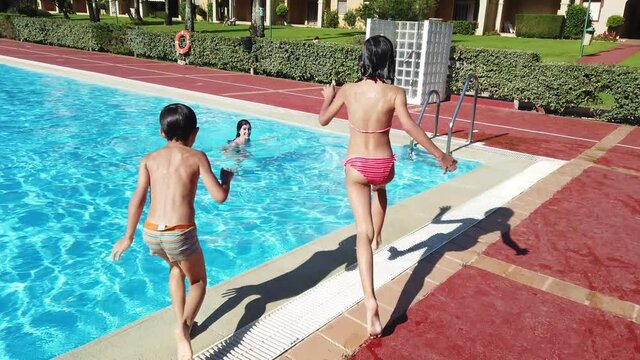 Family plays in the pool in summer, the children run with their mother