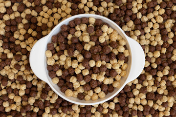 chocolate cereal bowl on cereal texture, cereal balls as background, top view
