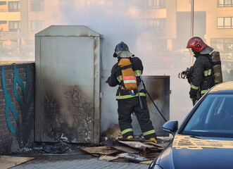 Firefighters extinguishing garbage can fire in car park