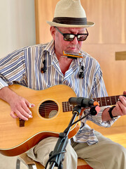 The musician playing blues, acoustic guitar, blues harmonica.