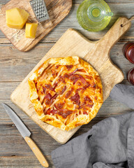 Galette or pie with turkey meat and parmesan and mozzarella cheeses on a serving board on a gray wooden culinary background top view. Delicious homemade hearty pastries