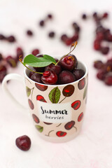 Sweet cherries in a tea mug on pink colored background
