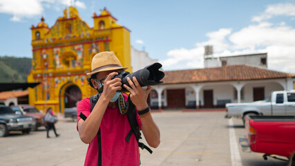 A young man with a protective mask taking photos with a camera in front of emblematic churches of...