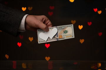 Man hand holds bill and hearts made of paper