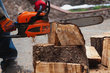 Chainsaw hands sawing large piece of wood