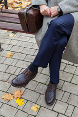 Man sits on bench in autumn  park. Near carpetbag