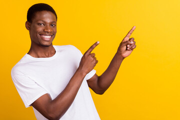 Portrait of attractive cheerful guy demonstrating ad offer decision isolated over bright yellow color background