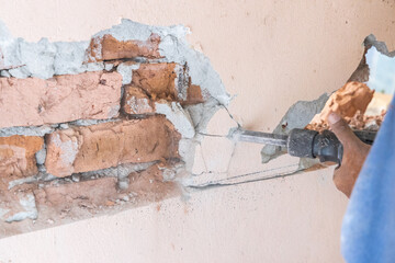 Worker use demolition hammer drill to break up wall surface. Motion blur intended.