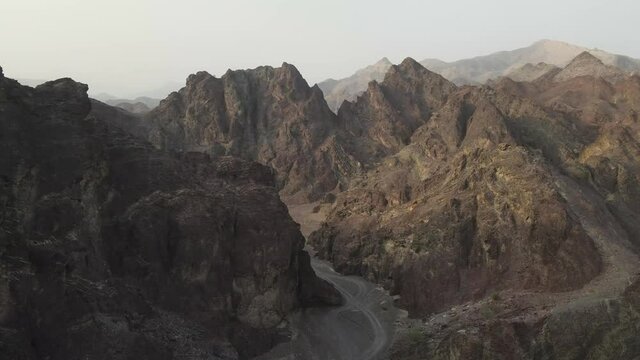 An aerial slow cinematic 4k video over the Hajar Mountains in the UAE showing red and brown rugged mountains 