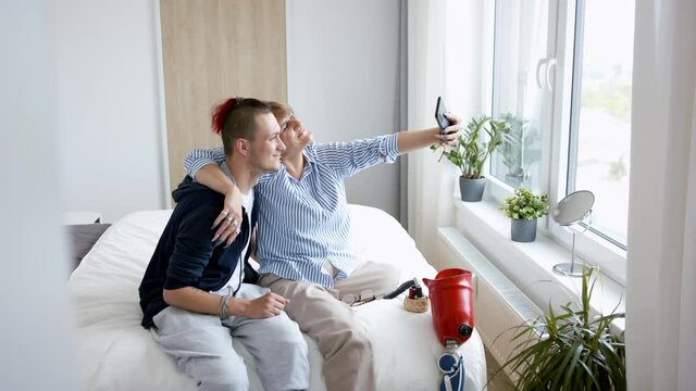 Disabled people taking selfie on bed indoors at home, leg amputee and prosthetic concept.