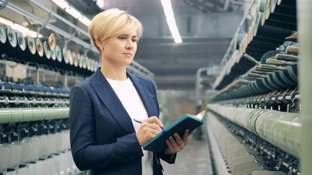 Female expert is taking notes in the textile factory unit