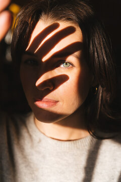 Woman holding hand up to light creating shadow on face