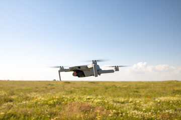 Fototapeta na wymiar Flying white drone with digital camera in green field