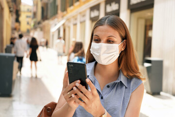 Travels with green pass. Attractive woman watching her mobile phone in city street. Tourism with...