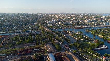 Fototapeta na wymiar Aerial view of the Kherson city. A shipyard on the banks of the Dnieper River of which there are cranes and ships. Residential area with houses and greenery