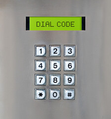 Intercom number pad with "dial code" message. Close up of stainless steel brushed metal texture. Used to input or type on devices, parking meters, intercom, digital locks and vending machines.