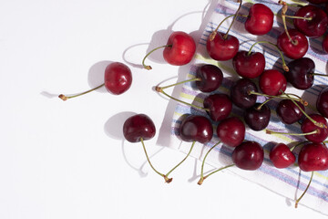 Naklejka na ściany i meble Washed fresh cherries on a kitchen towel on a white background, harvest of summer berries.