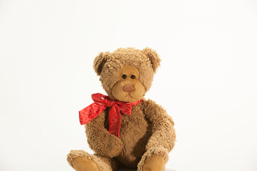A toy teddy bear sitting on the white background with copy space.