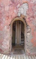 Arched doorway entrance to an old  deteriorating building, wall painted in pink