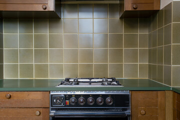 Interior of a old retro vintage kitchen with antique oven with brown wooden cabinets, green old school stylish tiles,needs renovation