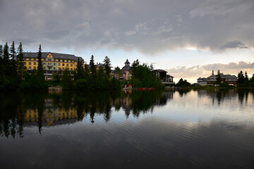 Fototapeta na wymiar Strbske pleso, lake and small town, in the evening. Buildings and trees reflecting in the lake. High Tatras, Slovakia.
