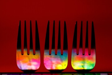 Three forks reflecting colorful colors. Abstract stylization. Red background.