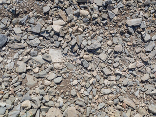 The texture of uneven roughly split gray small stones in close-up. The background of rubble in full screen.