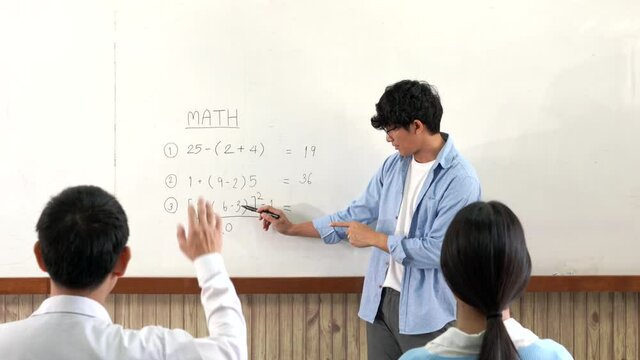 Educational concept a young smart male teacher explaining decision of hard math in a classroom