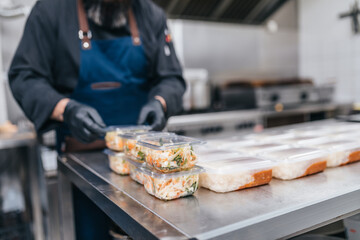 Food in disposable dishes ready for delivery. The chef prepares food in the restaurant and packs it in disposable lunch boxes.