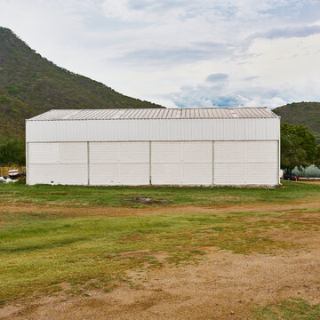 almac&eacute;n para guardar y fabricar productos, dentro de un campo cerca de una colina con un cielo muy bonito