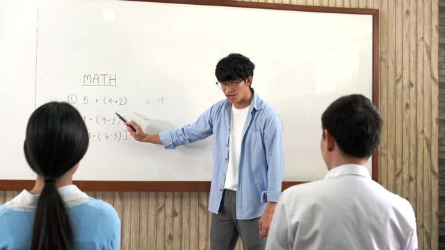 Educational concept a young smart male teacher explaining decision of hard math in a classroom