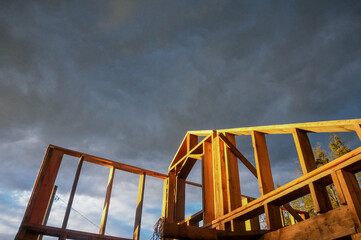 New home construction framing over dramatic sky