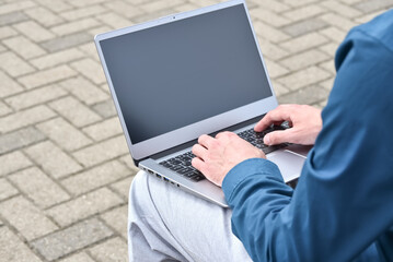 Laptop computer and man hands while working remotely on the computer outdoors.  Freelance programmer works remotely. Student using computer for learning, online education concept.