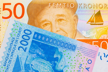 A macro image of a gray and orange fifty kronor note from Sweden paired up with a blue, two thousand West African franc bank note.  Shot close up in macro.