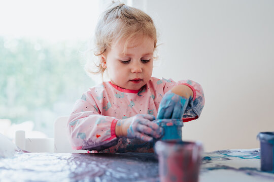 Adorable little two year old girl sitting finger painting