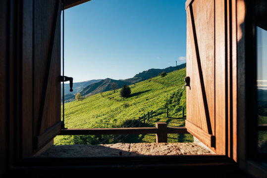 Fototapeta Breathtaking scenery of grassy mountain valley from wooden window