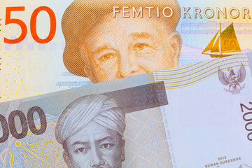 A macro image of a gray and orange fifty kronor note from Sweden paired up with a grey two thousand Indonesian rupiah bank note.  Shot close up in macro.