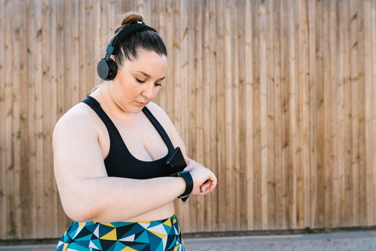 Sportive curvy woman checking fitness tracker