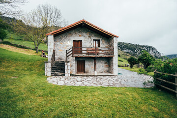 Small residential cottage on grassy hill under overcast sky
