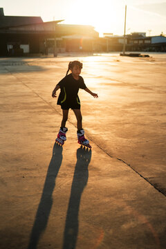 Asian girl playing rollerblades on a concrete patio